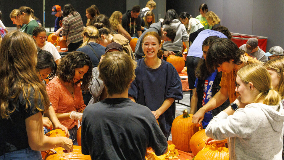 Group of students carving pumpkins and smiling.