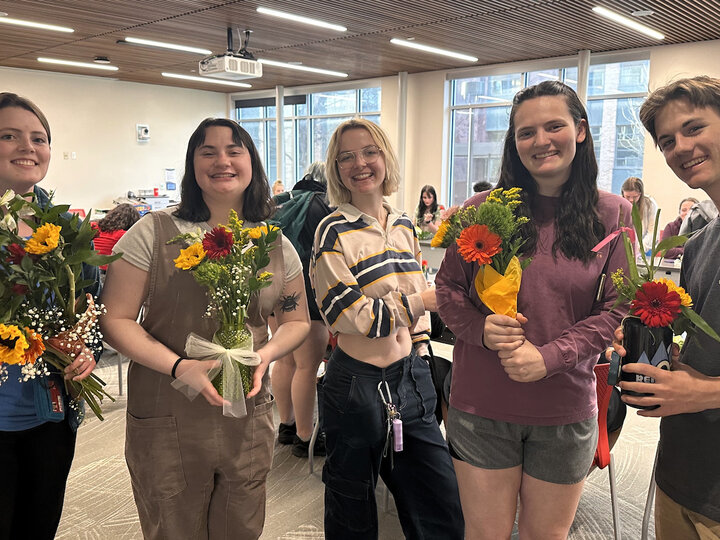 Students posing with flower bouquets. 
